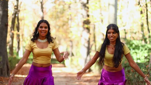 Two indian women performing traditional bollywood dance in a park