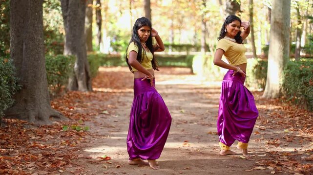 Two indian women dancing a bollywood choreography in an autumn park