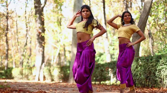 Two young indian women performing a bollywood dance in a park