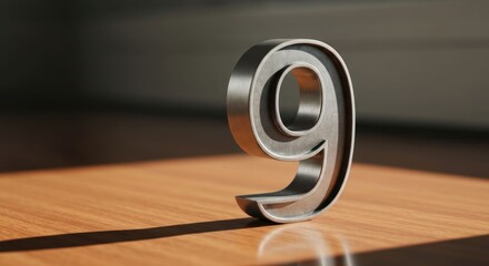 Metallic numeral nine on polished wood, sunlit
