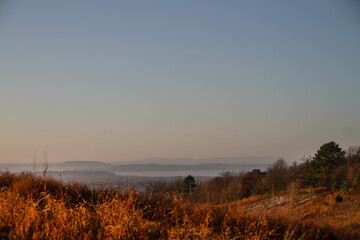 Oklahoma mountaintop view of lake at sunrise with grasses and trees in the foreground