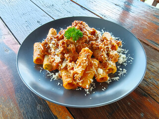 Side view of Pasta. tomato sauce, parmesan cheese, minced pork with rigatoni on a wooden table. Italian food