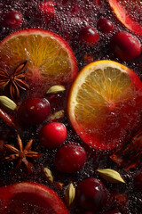 Mulled wine. The rich, red liquid with slices or whole oranges and cranberries floating within it. The background is filled with spiced sticks like star anise 