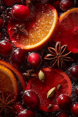 Mulled wine. The rich, red liquid with slices or whole oranges and cranberries floating within it. The background is filled with spiced sticks like star anise 