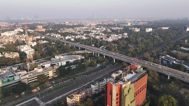 Aerial footage captures a Delhi Metro train departing from the Modi Mill Flyover near Sukhdev Vihar, as a tranquil sunset bathes South Delhi in warm golden hues, blend of modern infrastructure