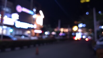 Blurred night view of city street traffic featuring vibrant colorful bokeh lights from vehicles and storefront signs in an abstract urban environment. © Ahmad