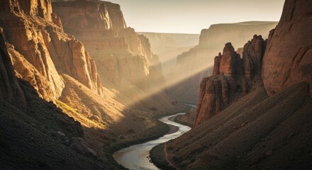 Sunlit canyon, river meanders through steep, rocky walls; golden hour light