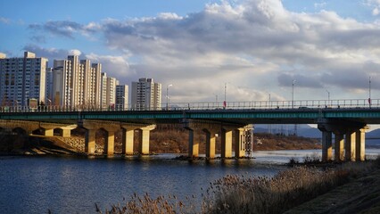 Fototapeta premium Urban River Bridge with Apartment Buildings Under Cloudy Sky