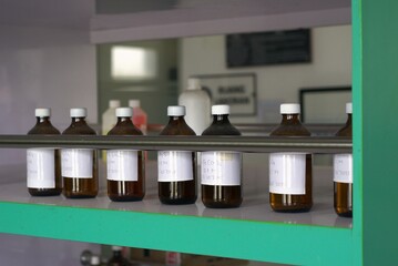 amber glass reagent bottles with white labels on a laboratory shelf