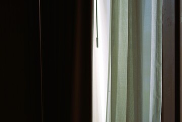 a soft morning light filtering through semi-transparent green curtains in a dark room