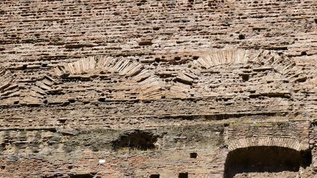 partially collapsed arched brick patterns rough masonry scattered holes mark ancient weathered wall structural decay centuries rome italy of historic roman ruins 