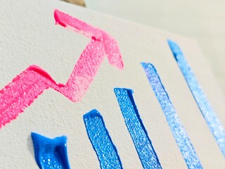 A high-angle macro shot of thick, textured acrylic paint on a white canvas forming a conceptual bar graph with a rising pink arrow, symbolizing business growth and financial success.