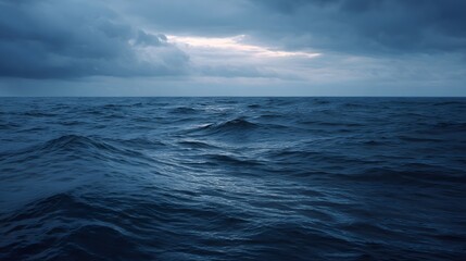 Fototapeta premium Turbulent deep blue ocean waves under a dramatic cloudy twilight sky conveying a powerful and atmospheric natural scene