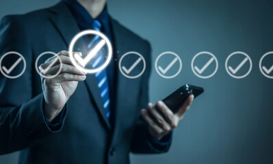 Businessman using smartphone and selecting virtual check mark icons, representing approval process, quality control, verification, compliance, success checklist, digital business workflow
