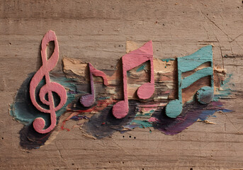 Wooden background with colorful painted music notes in artistic vintage style for creative music themes