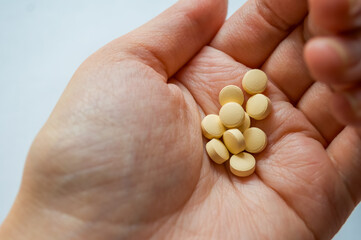 Human hand holding multiple yellow tablets