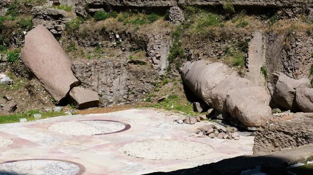 roman archaeological trench displays massive fallen stone column beside geometric marble floor fragment rubble metal supports appear tempio del divo romolo close view rome italy empire 