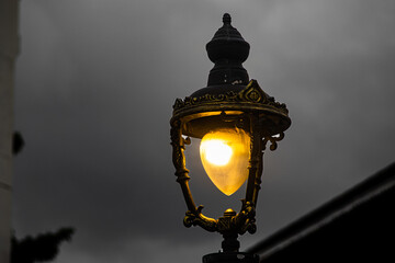 Vintage Street Lamp Glowing at Dusk with Dark Cloudy Sky Background