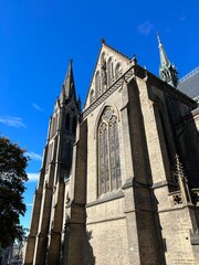 st vitus cathedral in prague. Gothic Church Facade Against Blue Sky. Historic gothic church exterior with tall tower and stained glass windows under clear blue sky.