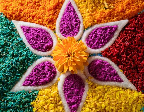 close up of rangoli pattern made with colored rice and flowers top view