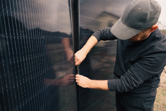 Worker hands connecting MC4 solar connectors on a photovoltaic panel background.
