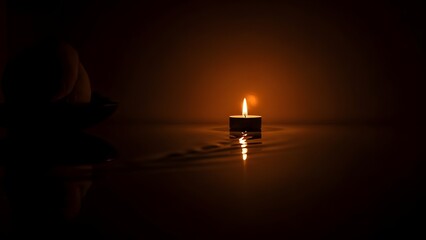 A glowing yellow flame on a burning wax candle flickers against the black night, casting a warm light through the darkness with the heat and glow of a holy Christmas candlelight