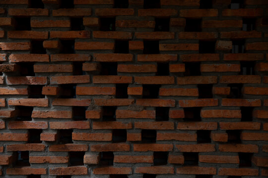 Aesthetic perforated red brick wall with natural light and shadow patterns.