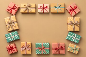 Fototapeta premium Soft gift box frame arranged on light brown background, warm neutral tones, minimal decoration, and spacious center for text
