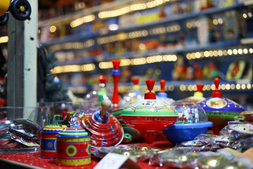 Colorful vintage spinning tops displayed in a shop with soft bokeh lights. Classic tin toys evoke nostalgia, holiday gifting, retail merchandising, and playful childhood memories.