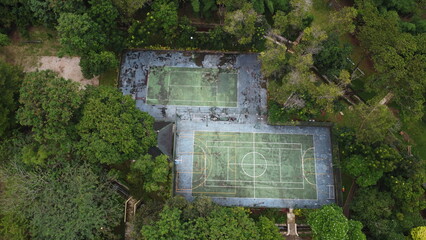 Aerial View of Abandoned Tennis and Basketball Courts Surrounded by Trees. © Arfee