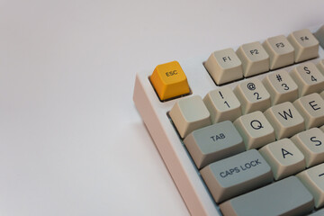 White mechanical keyboard with bright yellow Esc key on white background, minimalism, keyboard...