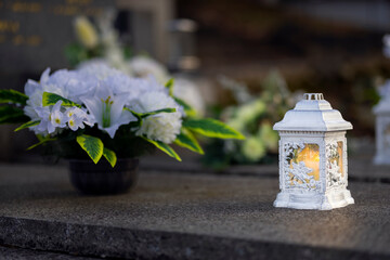 Lit burning candle at night on black stone monument in cemetery. Memory of the deceased. Expression of love