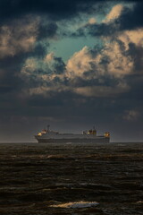 Ship on the horizon under cloudy sky