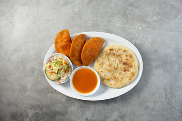 A top down view of a plate of a pupusa and pastelitos.