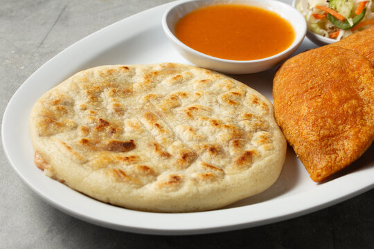 A closeup view of a plate of a pupusa and pastelito.