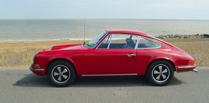 Classic Red Porsche 912 parked on seafront promenade.