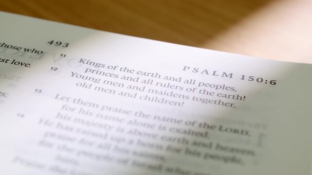 Macro footage of English Bible as pages turn to Psalm 150 and reveal Proverbs. Clear printed text and soft lighting make this clip ideal for worship media, christian study and faith projects