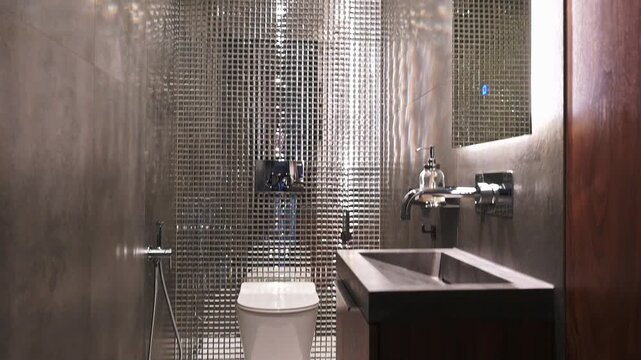 sleek, compact bathroom with a metallic mesh wall backdrop, modern sink, minimalist toilet, and dark wood vanity; clean lines and industrial aesthetic