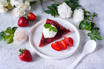 A piece of strawberry pie with a scoop of ice cream for dessert on a white plate on a light background. Close-up