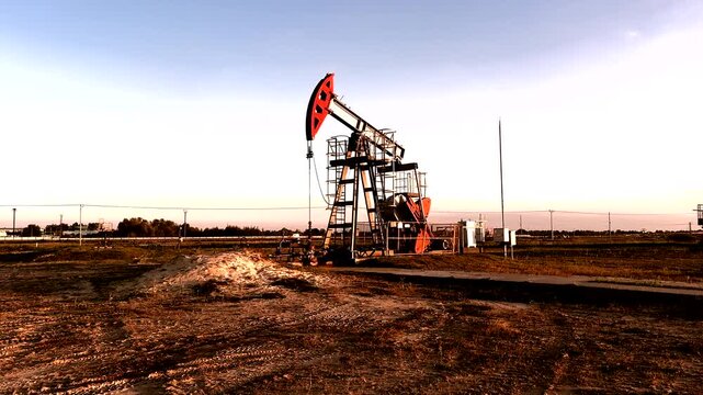 Crude pump jack on sunrise in oil field. Oil Pump Jack Operates on Beautiful Sunset at Oil Field in Industrial Area. Oil drill rig, drilling derrick in oilfield. Crude petroleum industry. 
