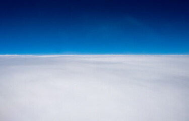 Une vue au-dessus des nuages avec un ciel bleu d&eacute;grad&eacute; depuis le hublot d'un avion