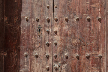 Fototapeta premium Weathered Wooden Door With Iron Studs and Keyhole