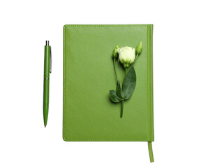 A vibrant green notebook and pen beside a white flower on a dark background