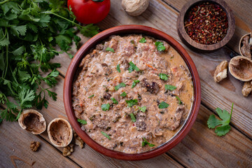 Kharcho in Megrelian style with walnuts on a brown plate on a wooden table. Top view. Close-up.