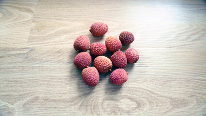 Fresh lychee fruits lying on wooden table. Tropical exotic litchi with red bumpy skin, juicy Asian...