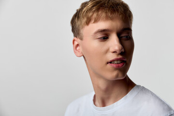 Fototapeta premium Male, young headshot with face and expression of contemplation, wearing white t shirt, side view against a neutral studio background, subtle mood and clean lighting