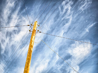 Utility poles and power lines under a blue sky with clouds showing electricity infrastructure and public utilities