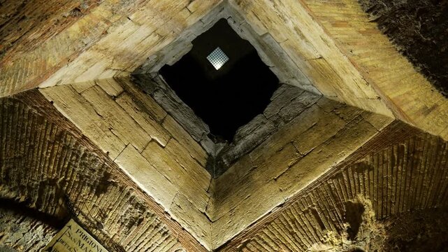 through rough hewn square opening layered ancient roman stone brickwork faint daylight contrasts textures castel sant'angelo reveals upward view rome italy empire emperor 