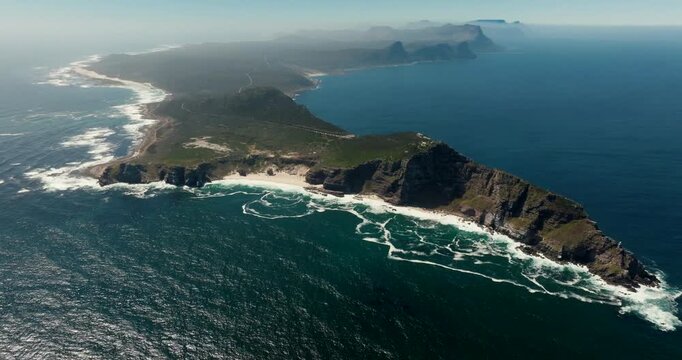 Wide aerial drone view of the Cape of Good Hope in South Africa Coastal cliffs, turquoise water, sandy beach, and green terrain on a sunny day. Perfect for travel, nature, and documentary footage.