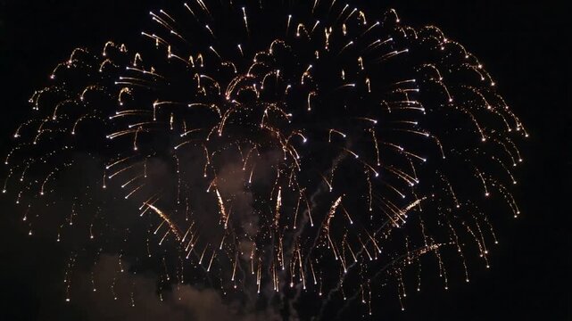 Spectacular burst of golden fireworks illuminating the night sky with dazzling patterns of light and sparks